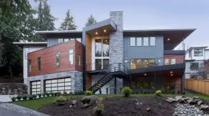 Two-story modern Bellevue Meydenbauer custom home design featuring mixed wood, stone, and metal exterior, large windows, an outdoor staircase, and a landscaped front yard.